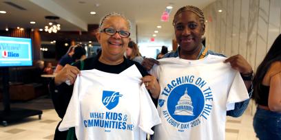 Photo of retired teacher Teresa Reaves and paraprofessional Tracy Romain of Boston Teachers Union holding up t-shirts that read "What Kids & Communities Need" and "Teaching on the Hill. AFT Lobby Day 2023," respectively